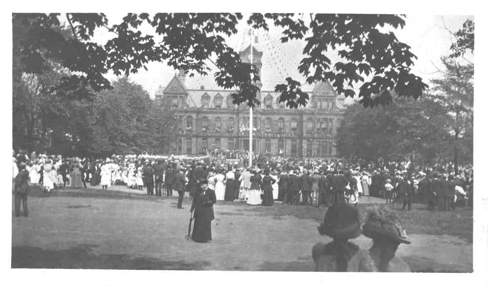 Black and white photo of group gathering in Grand Parade with City Hall in background.