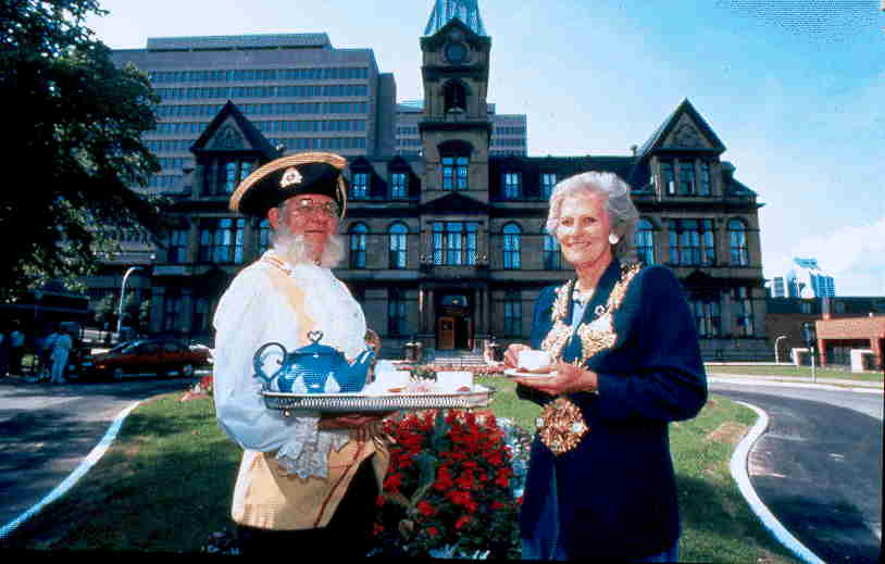 Colour photo standing outside City Hall holding a tray of tea.