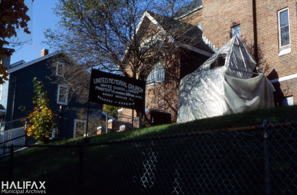 Colour photograph of the exterior of a church with the bell carillon covered by tarps.