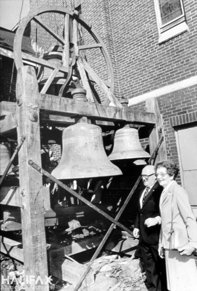 Black and white photograph of a man and woman beside church bell carillon