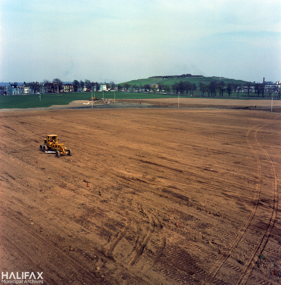 Colour photograph of a field being graded using heavy machinery