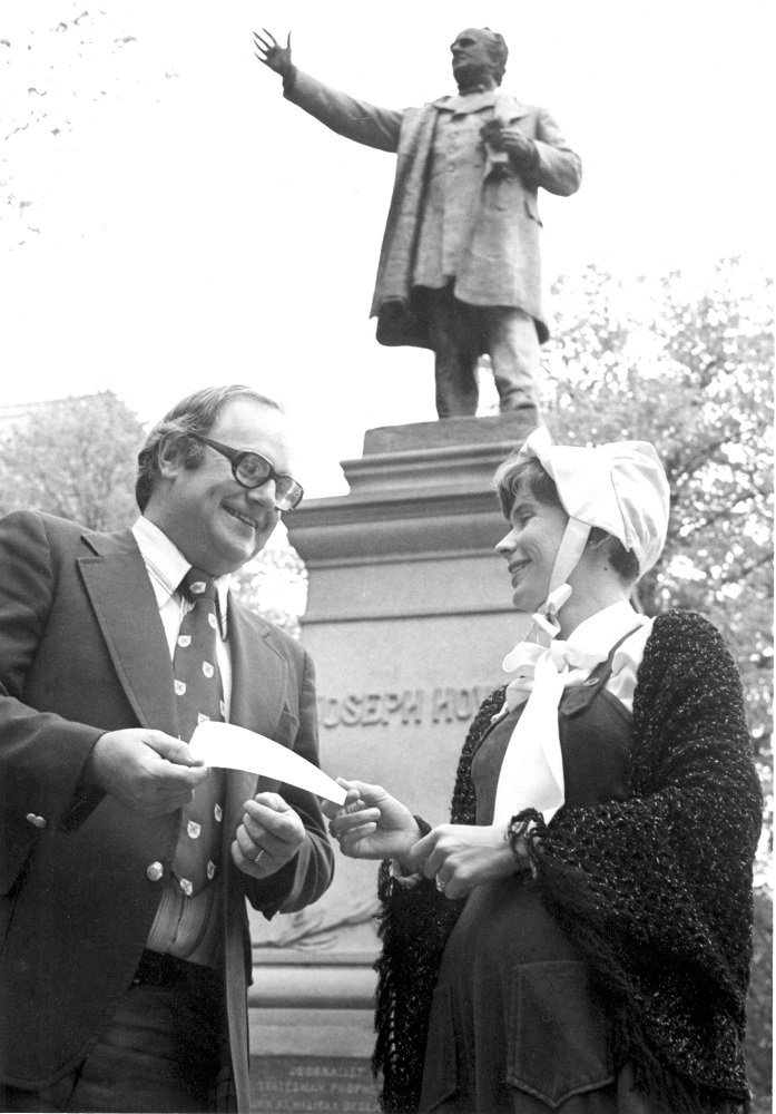 Black & white photo of Mayor Walter Fitzgerald presenting a cheque to Festival Vice-President, Carolyn Amirault in front of the Joseph Howe statue in the courtyard of Province House, 1978. 