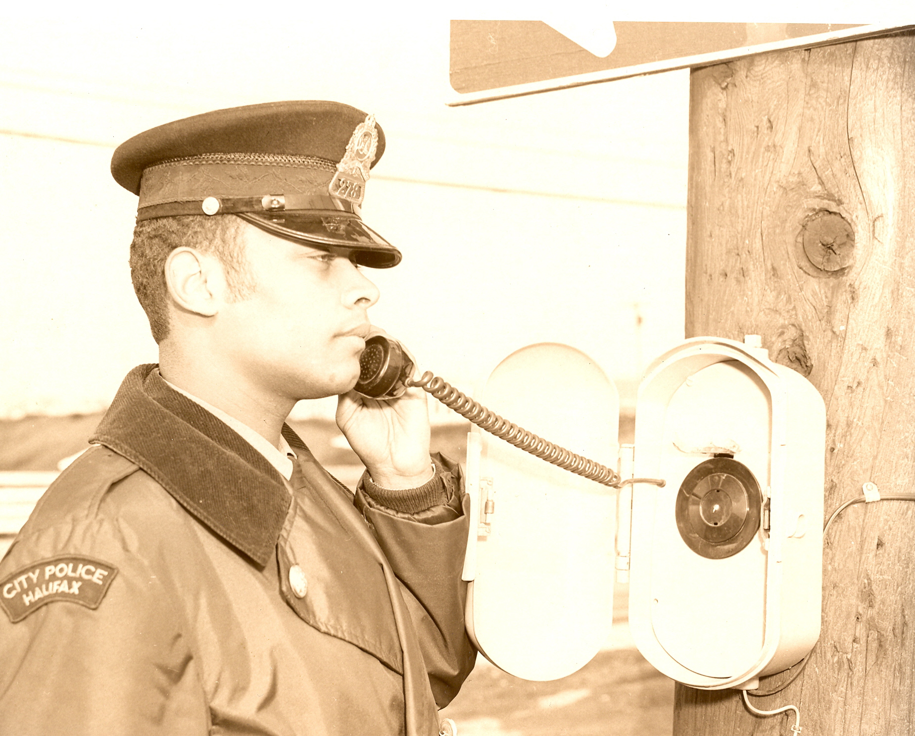 Black and white photo of African Nova Scotian officer using call-box