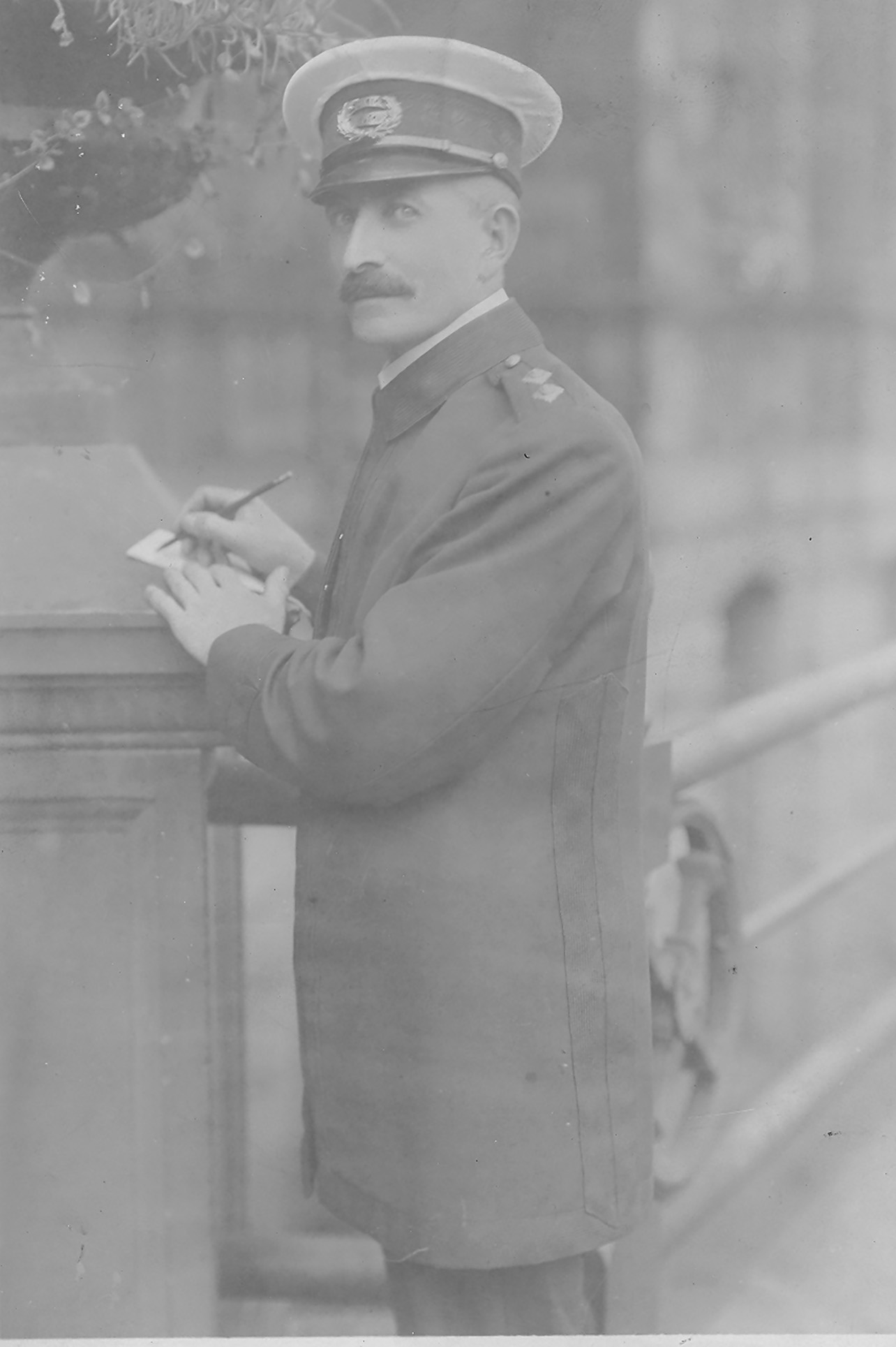 Black and white photo of policeman writing in a notebook on the pedestal at the Grand Parade entrance to City Hall.