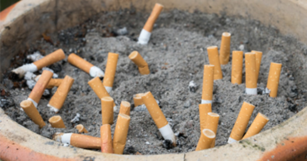 Close up picture of a clay pot filled with sand and several extinguished cigarette butts