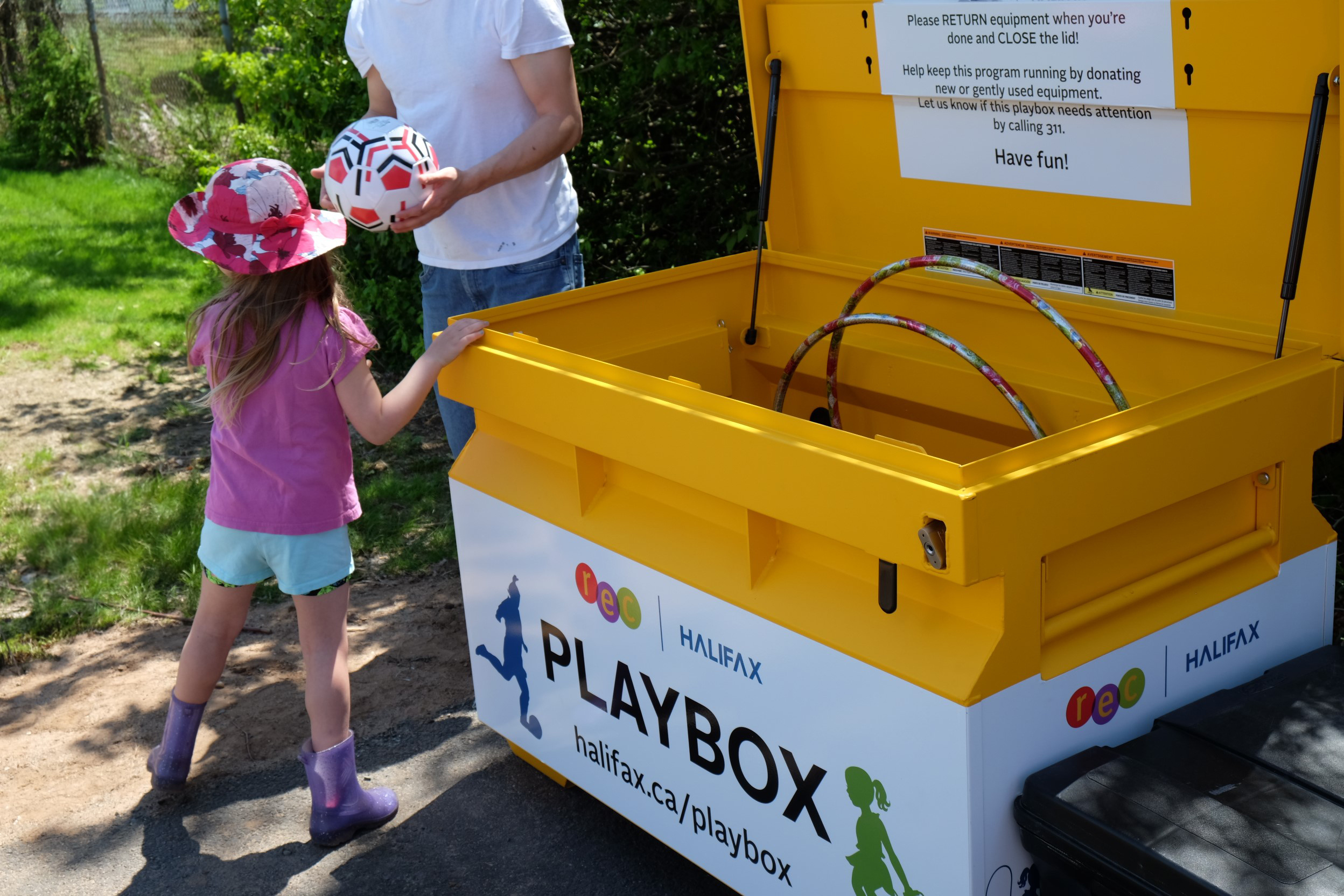 A child and parent borrowing a soccer ball from the playbox