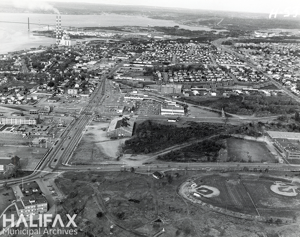 Black and white aerial photograph of a park with baseball diamonds and residential neighbourhood in the background.