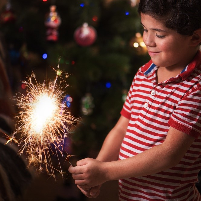 Child wearing a red polo holding a fireworks sparkler.