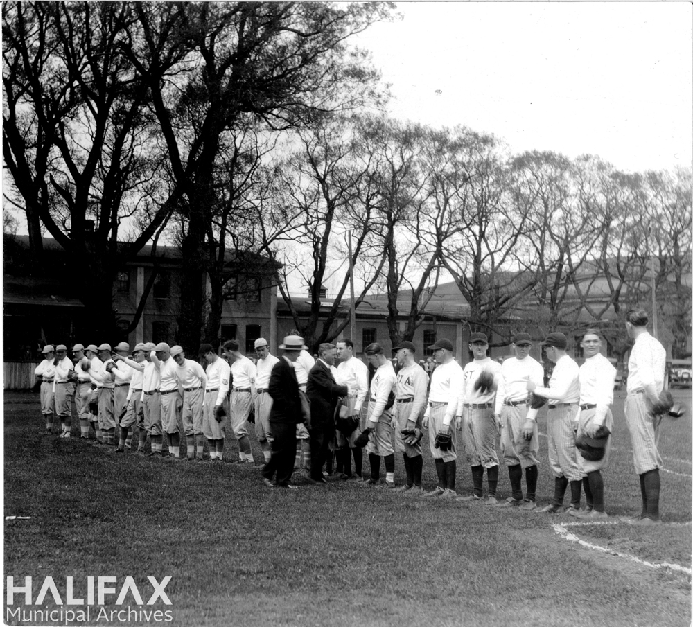 Black and white photograph of two baseball teams lined up as part of an opening game ceremony