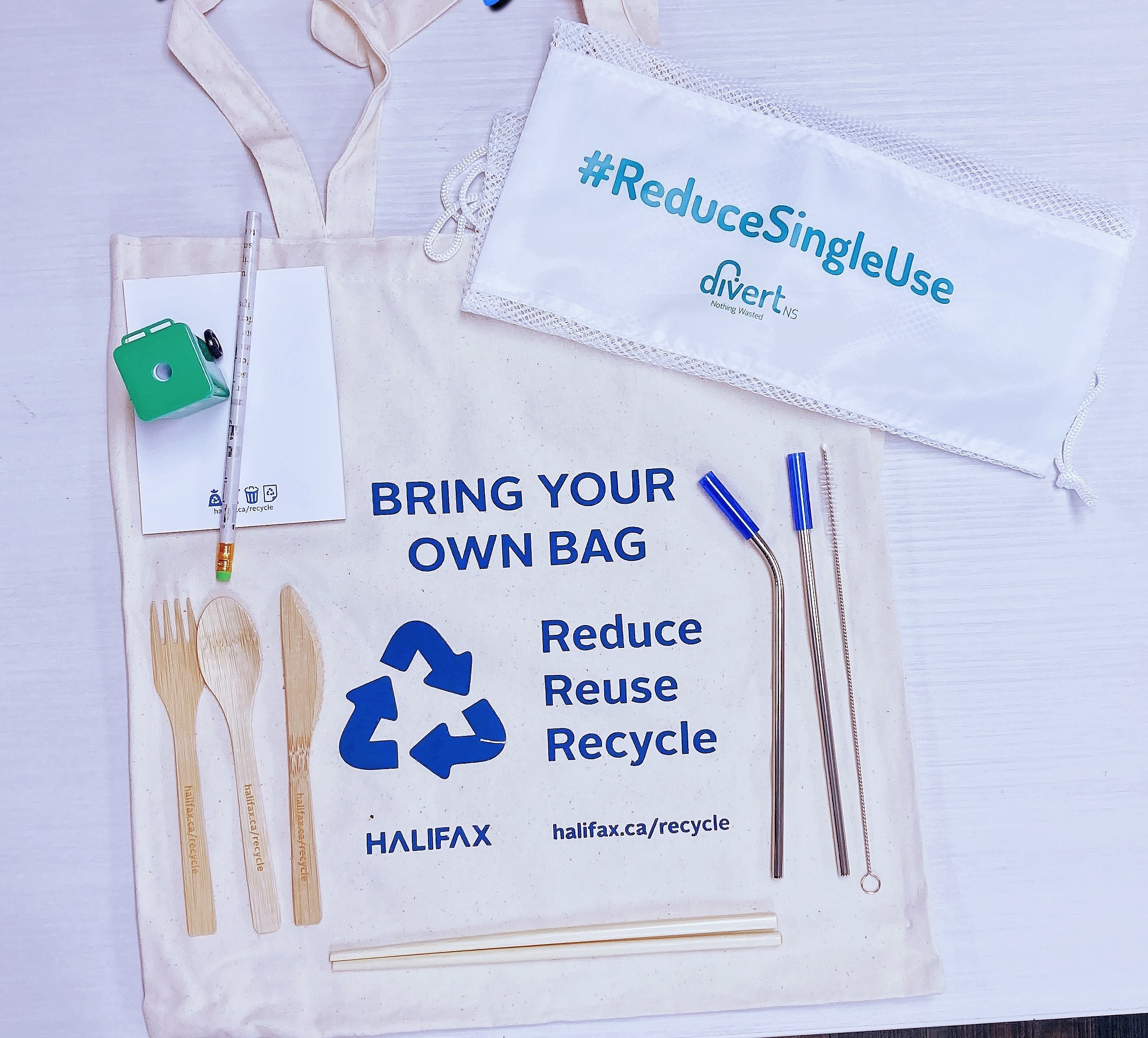 Zero Waste Prize Pack. The prize pack includes a canvas bag, a produce bag, a set of stainless-steel straws, a set of bamboo cutlery, a pencil sharpener, a pencil and a notepad.