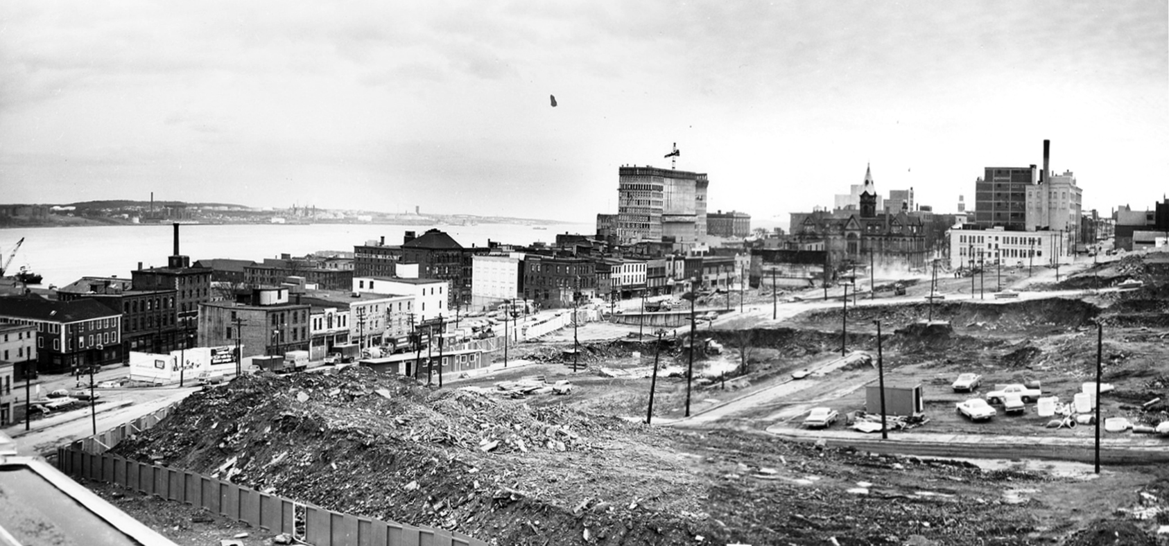 view of the Scotia Square excavation site as seen from the Trade Mart building. The view includes the Moir's Factory, City Hall, the Royal Bank of Canada (under construction), and some buildings along Barrington St.