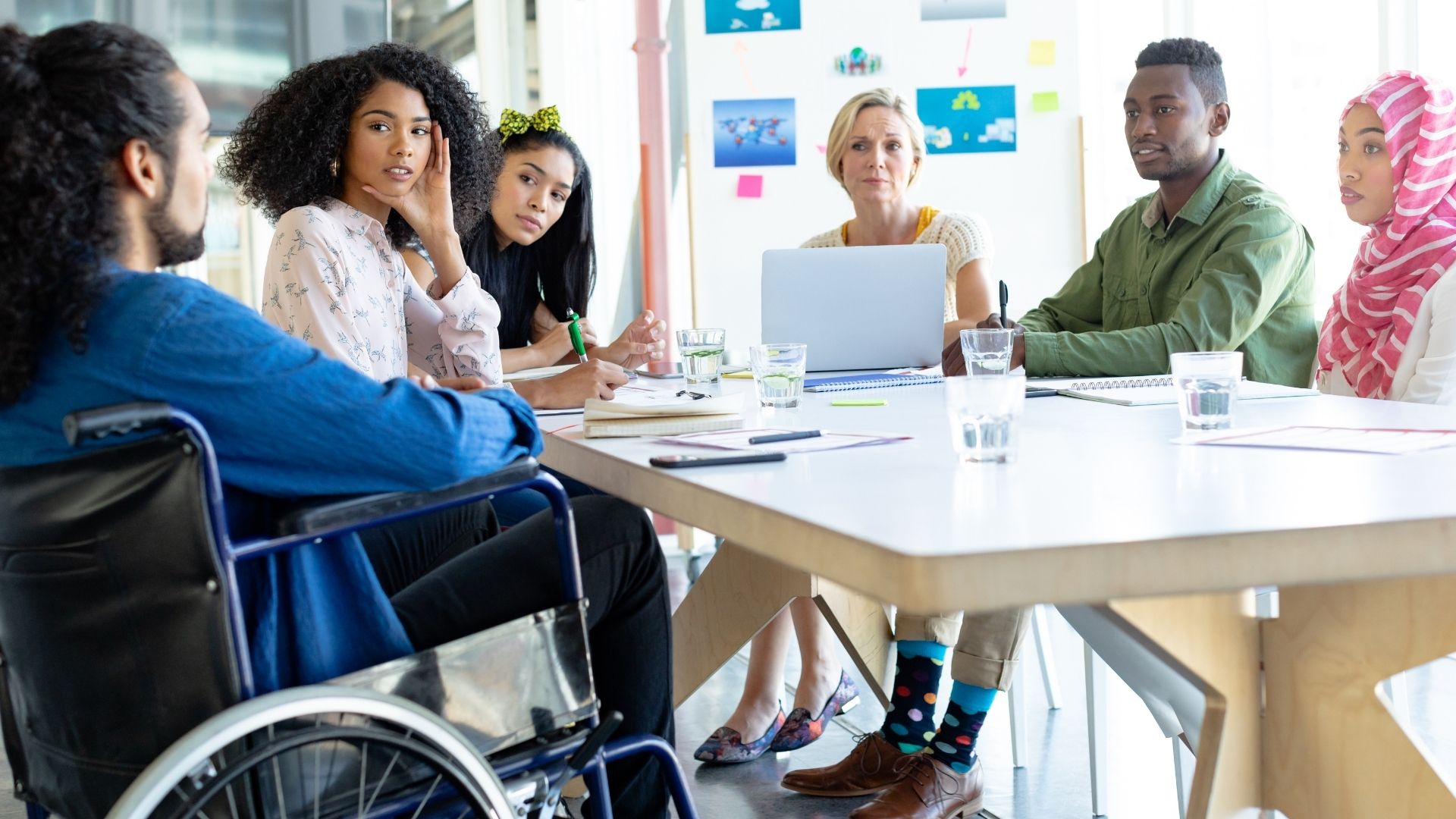 A diverse group of six people sitting together at a table having a discussion and taking notes