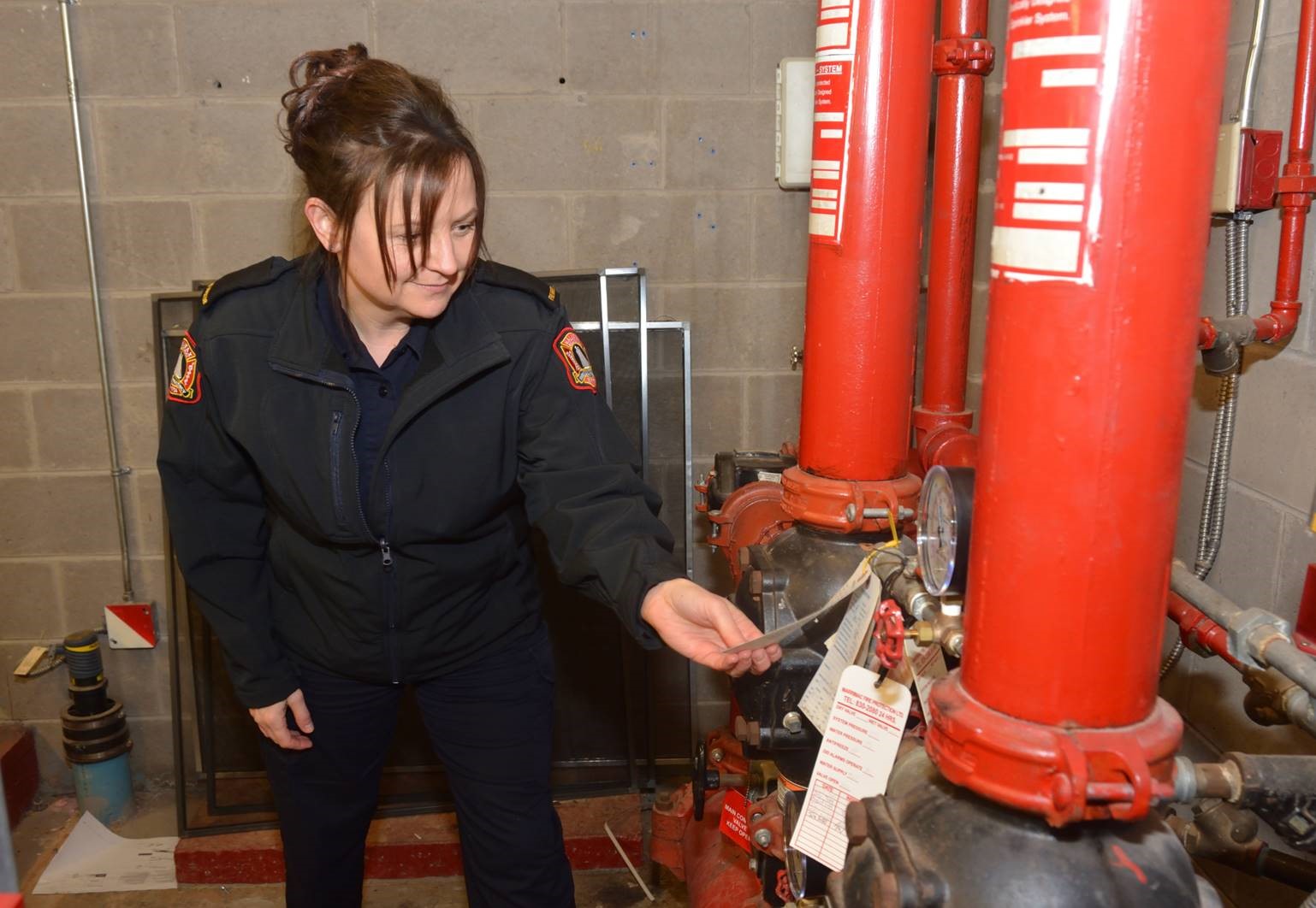 A female Fire Inspector inspects heating equipment ensuring that it is up to standard.