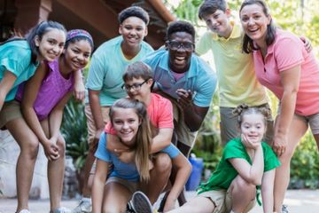 a group of inclusion staff and children participating in a camp huddle together for a photo