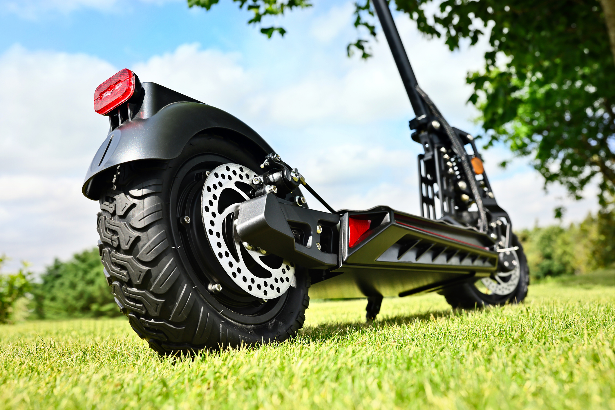 A view from the ground of an electric scooter on grass during a sunny day.