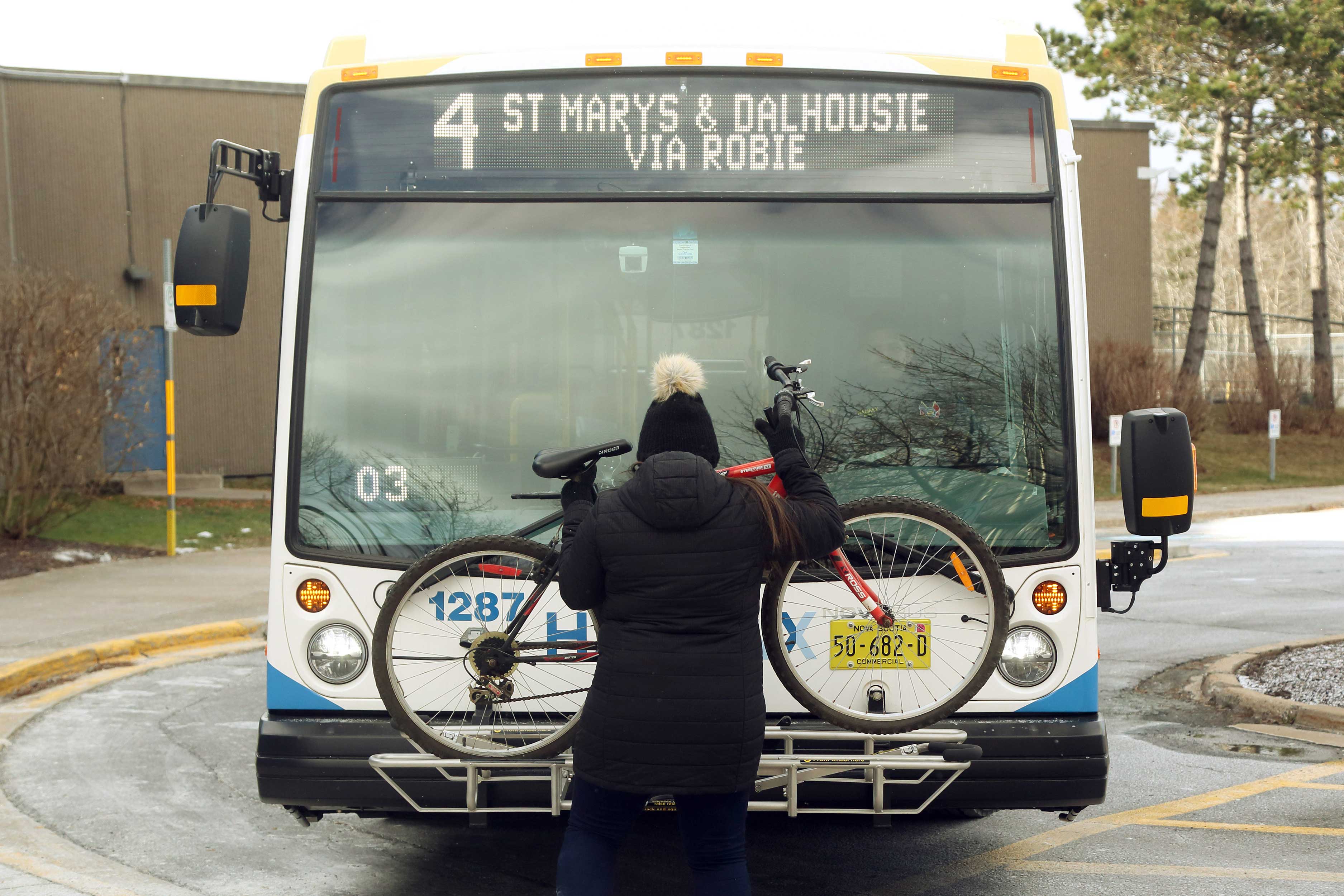 person loading bike on bike rack on the front of a bus