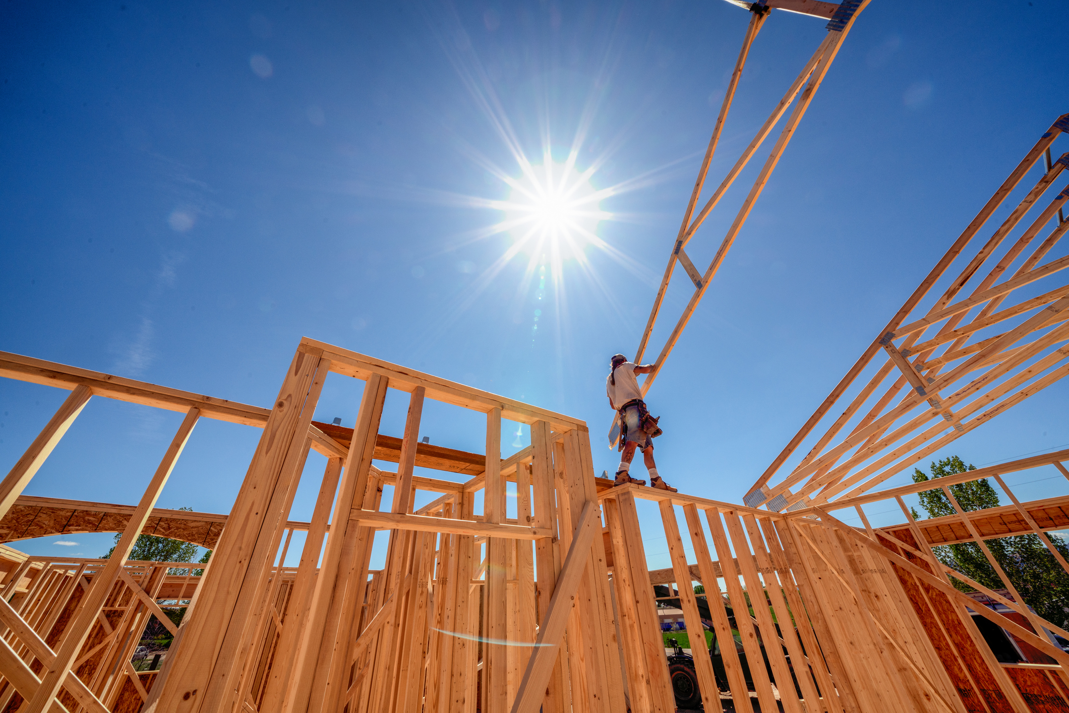 An image of a housing construction site with a man working under a blue sky 
