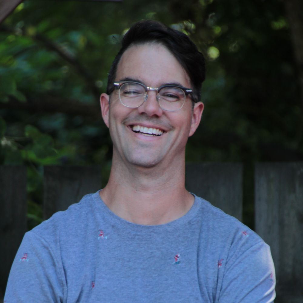 Man wearing glasses smiling at the camera.