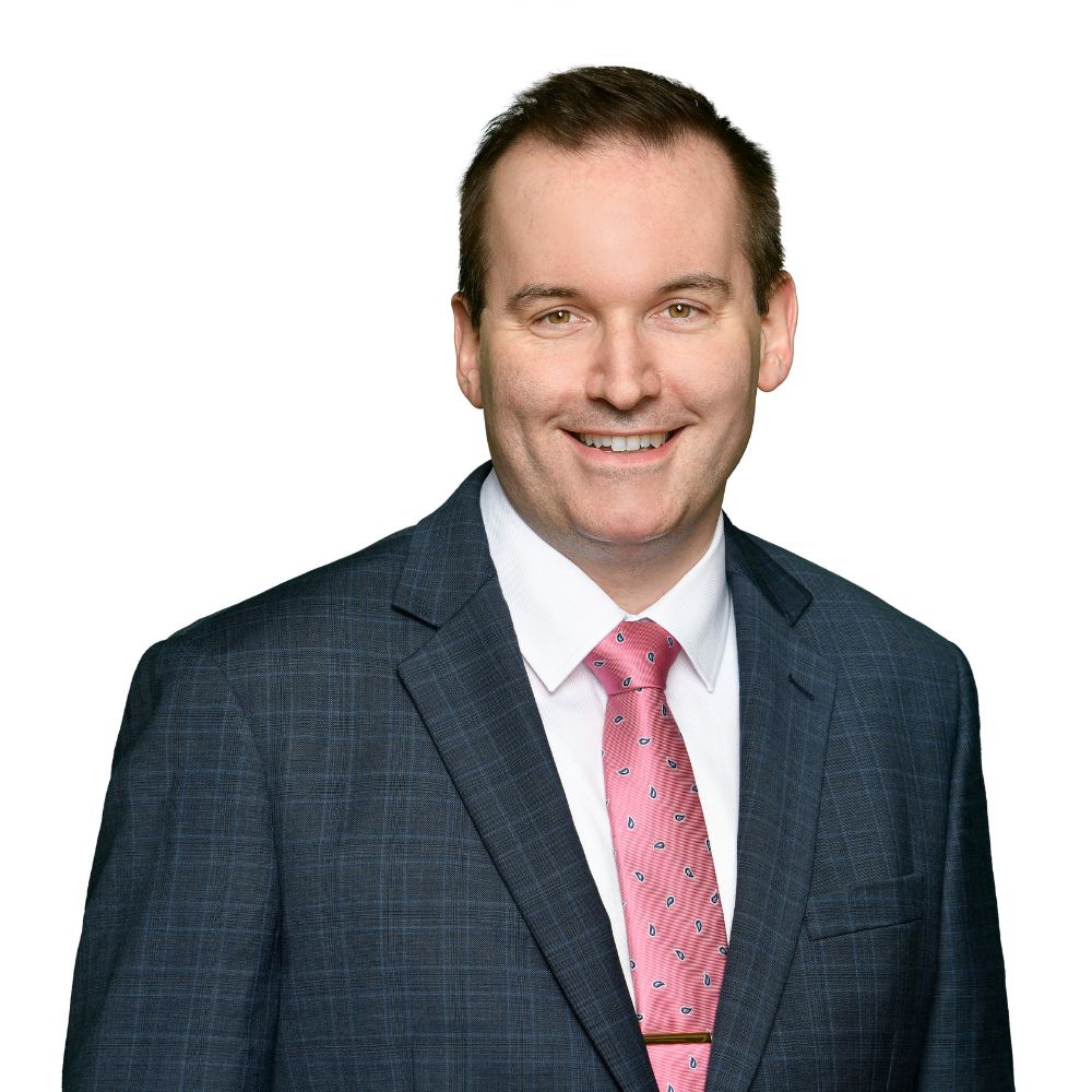 Man in suit and tie smiling at the camera.