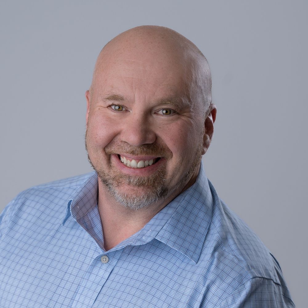 Man wearing button-up shirt smiling at camera.