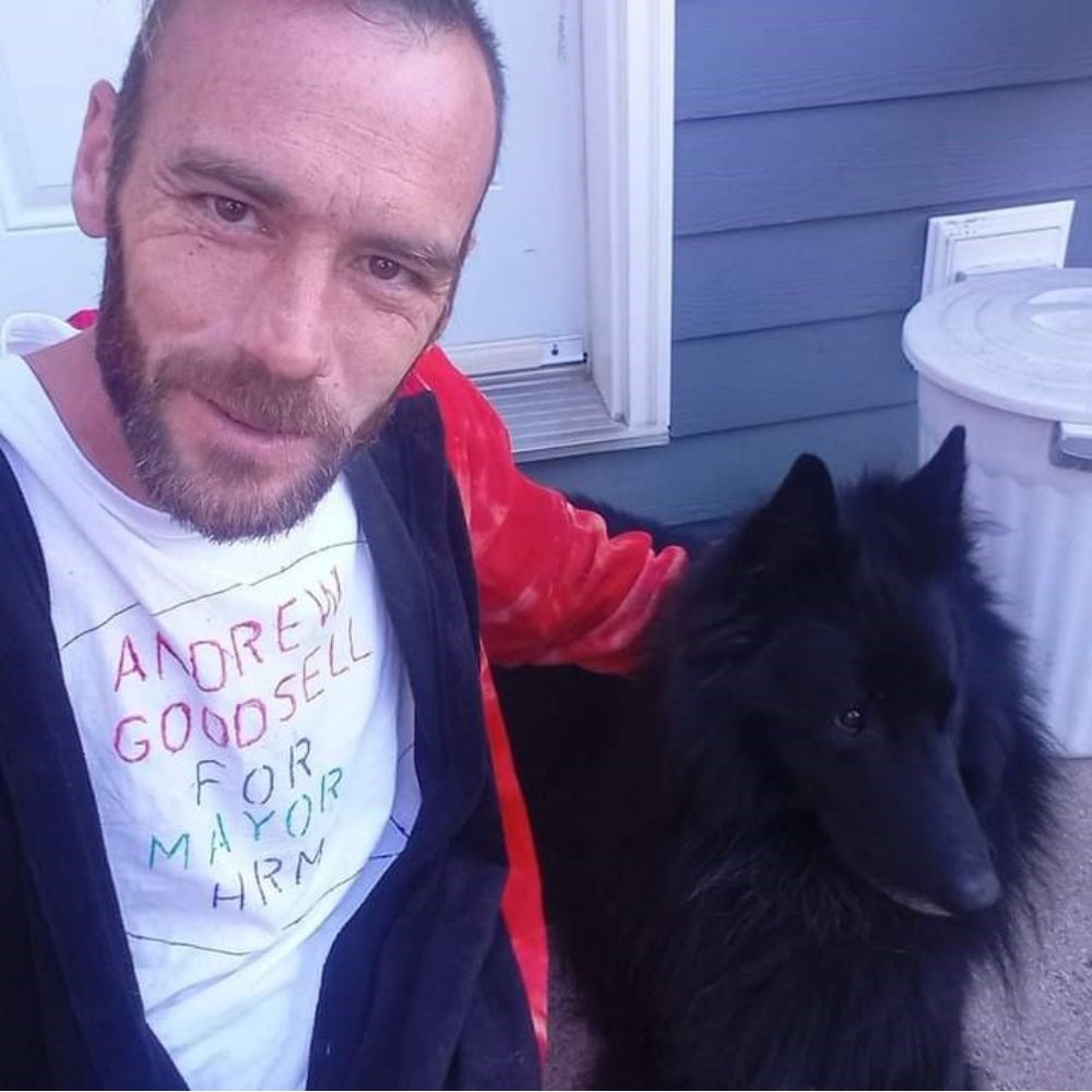 Man smiling at camera with a dog.