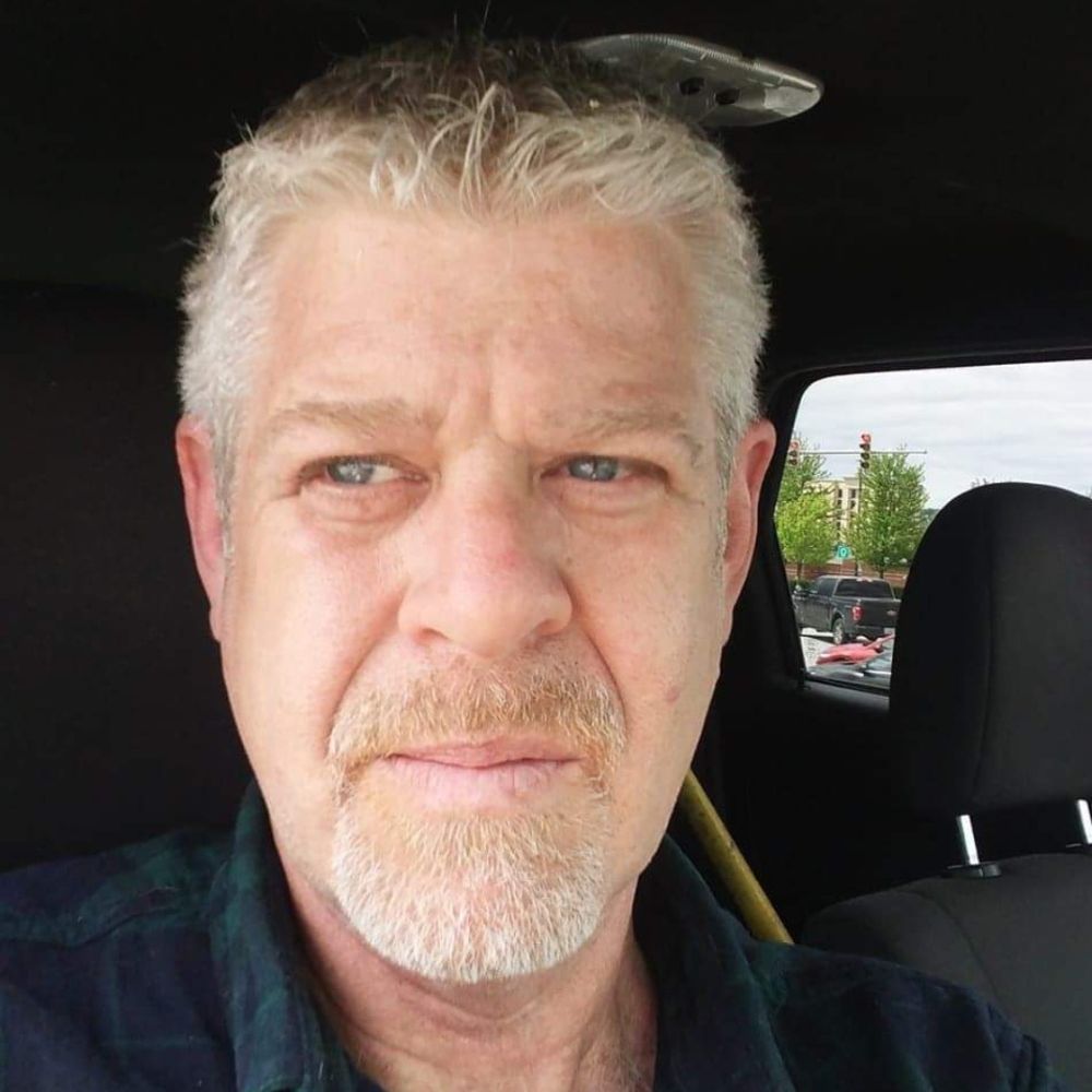 Man sitting in vehicle looking away from the camera.