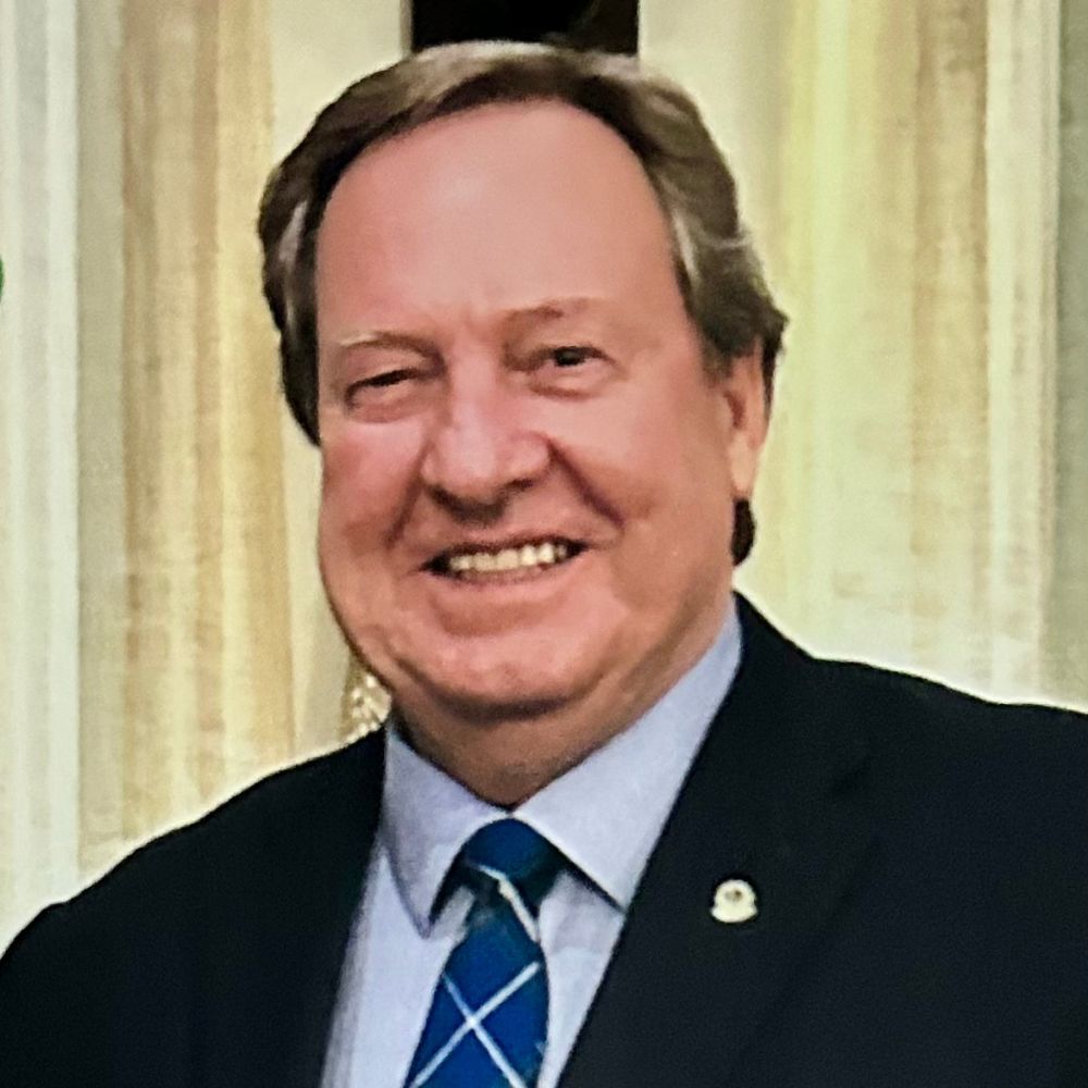 Man in suit and tie smiling at camera.