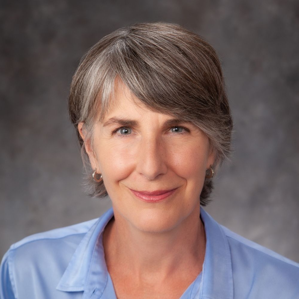 Woman wearing blue shirt smiling at camera.