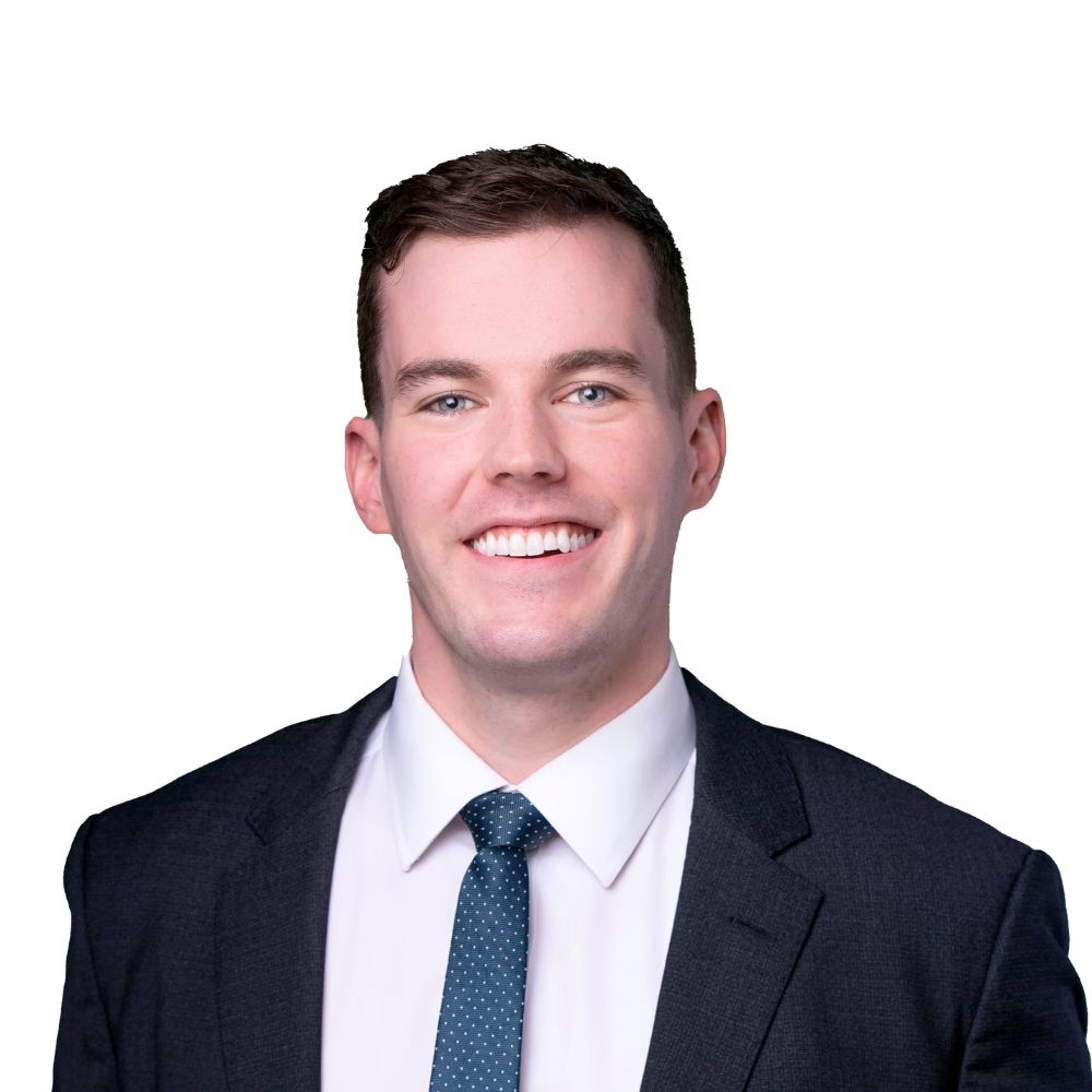 Man wearing a suit and tie smiling at the camera.