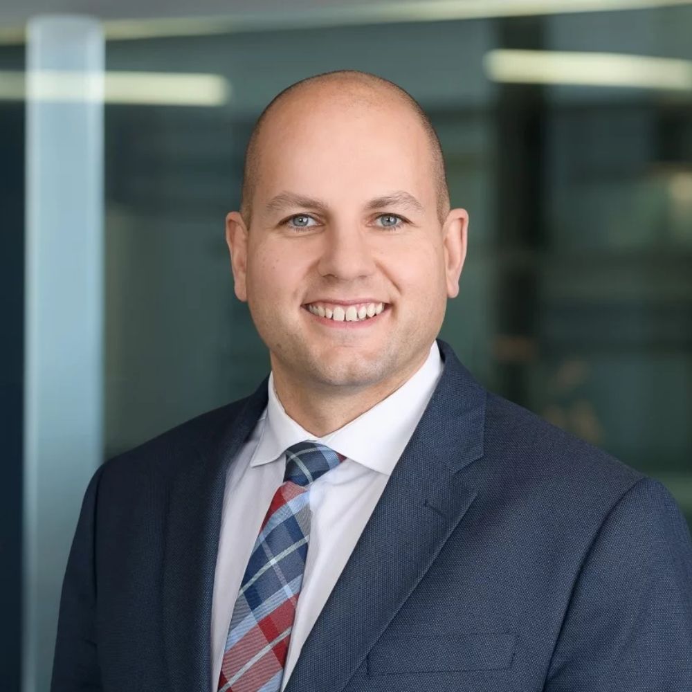 Man in a suit and tie smiling at the camera.