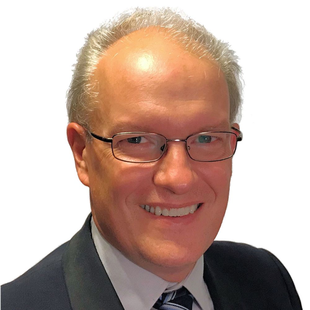 Man wearing suit and tie smiling at the camera.