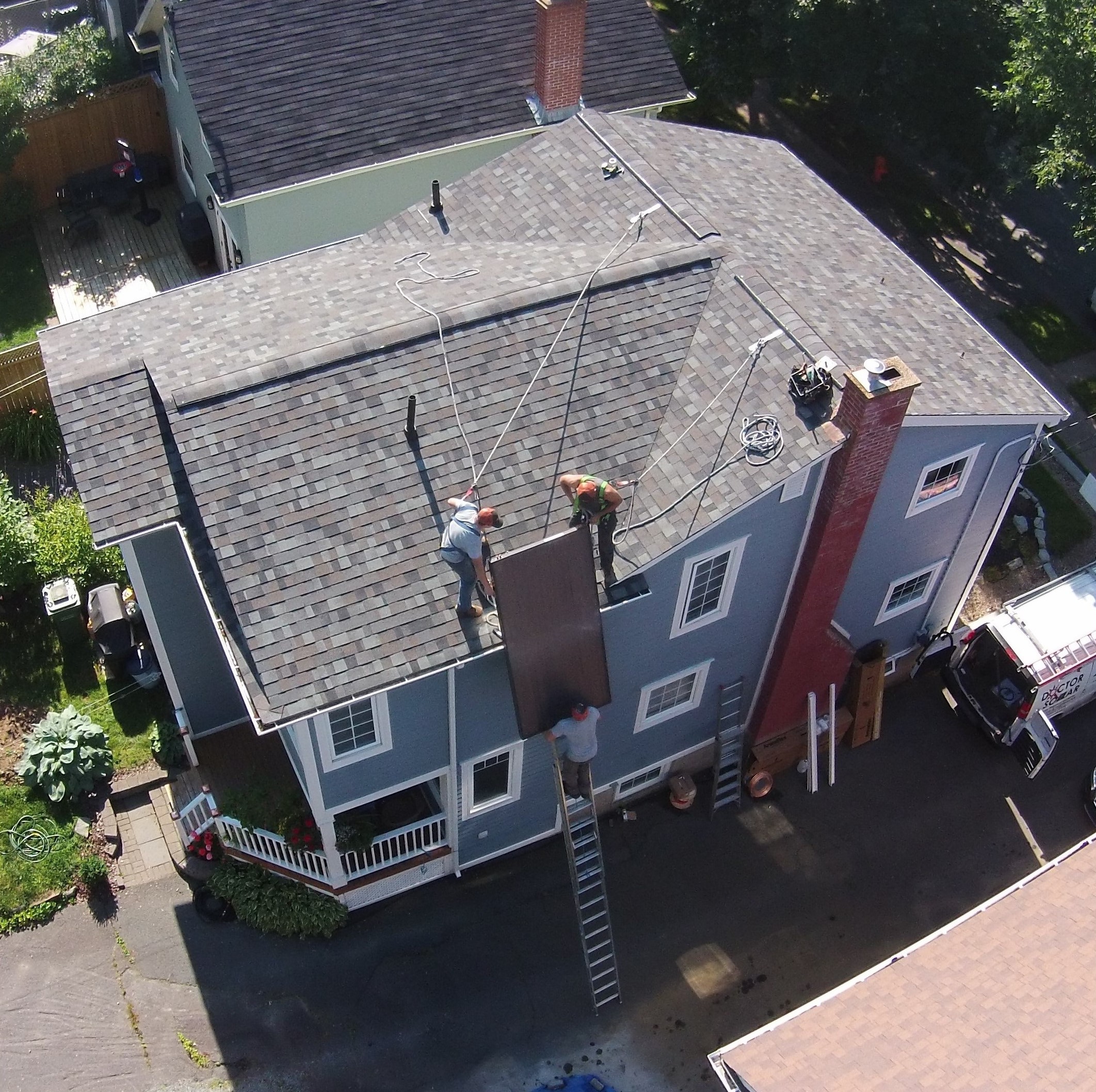 A top-down view of a rooftop with two people installing solar panels.