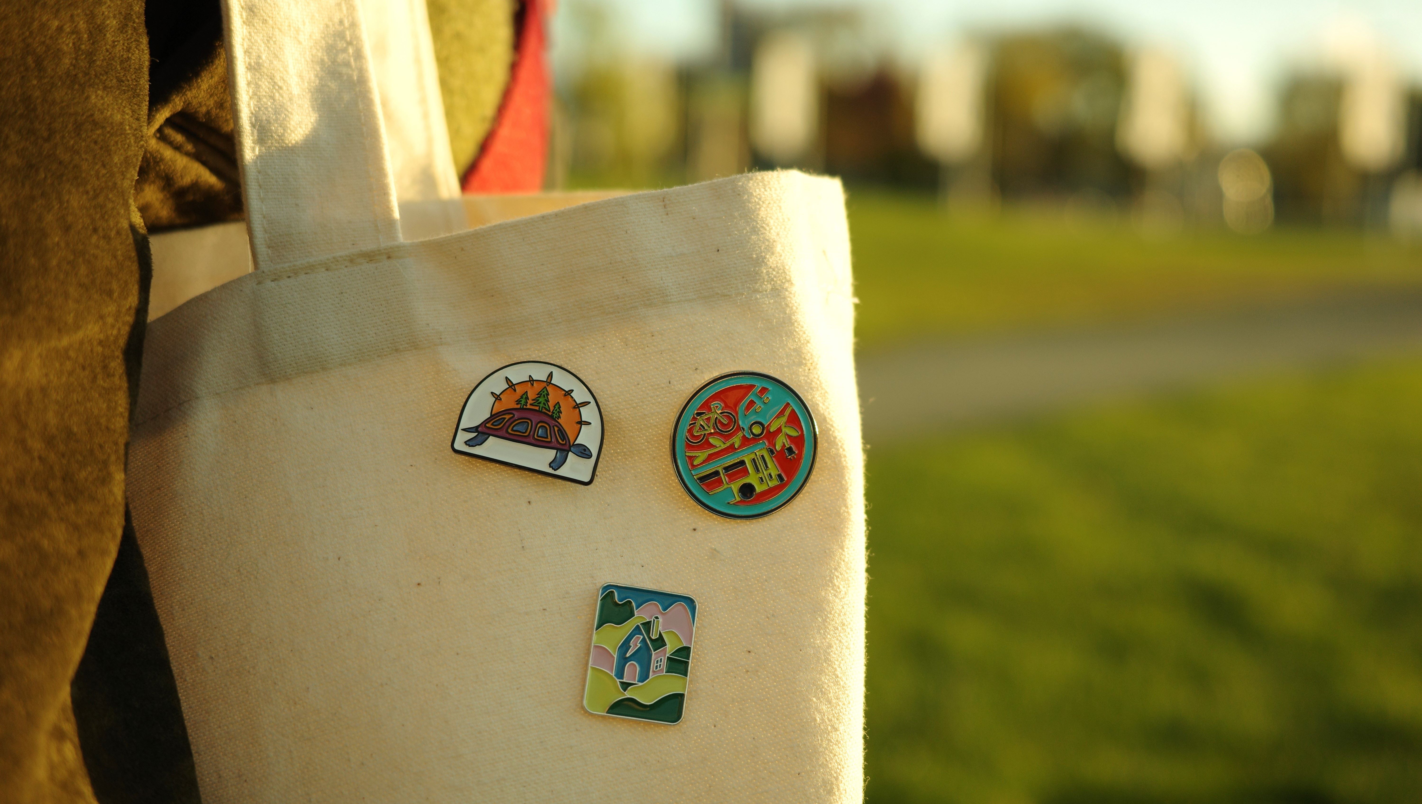 A canvas bag with the climate commitment badges pinned to it.