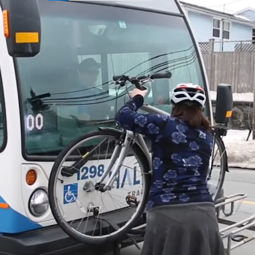 A woman installing her bike on the front rack of Halifax bus.