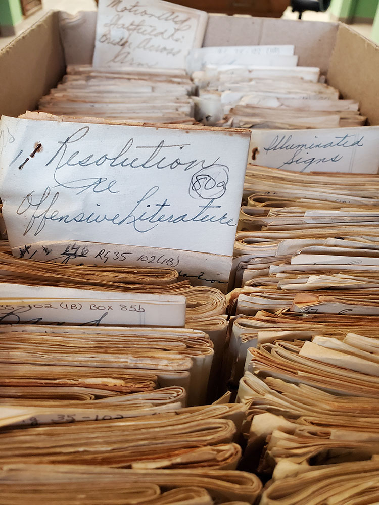 Close up of a box of folder papers with a couple sticking out from the rest with cursive text visible.