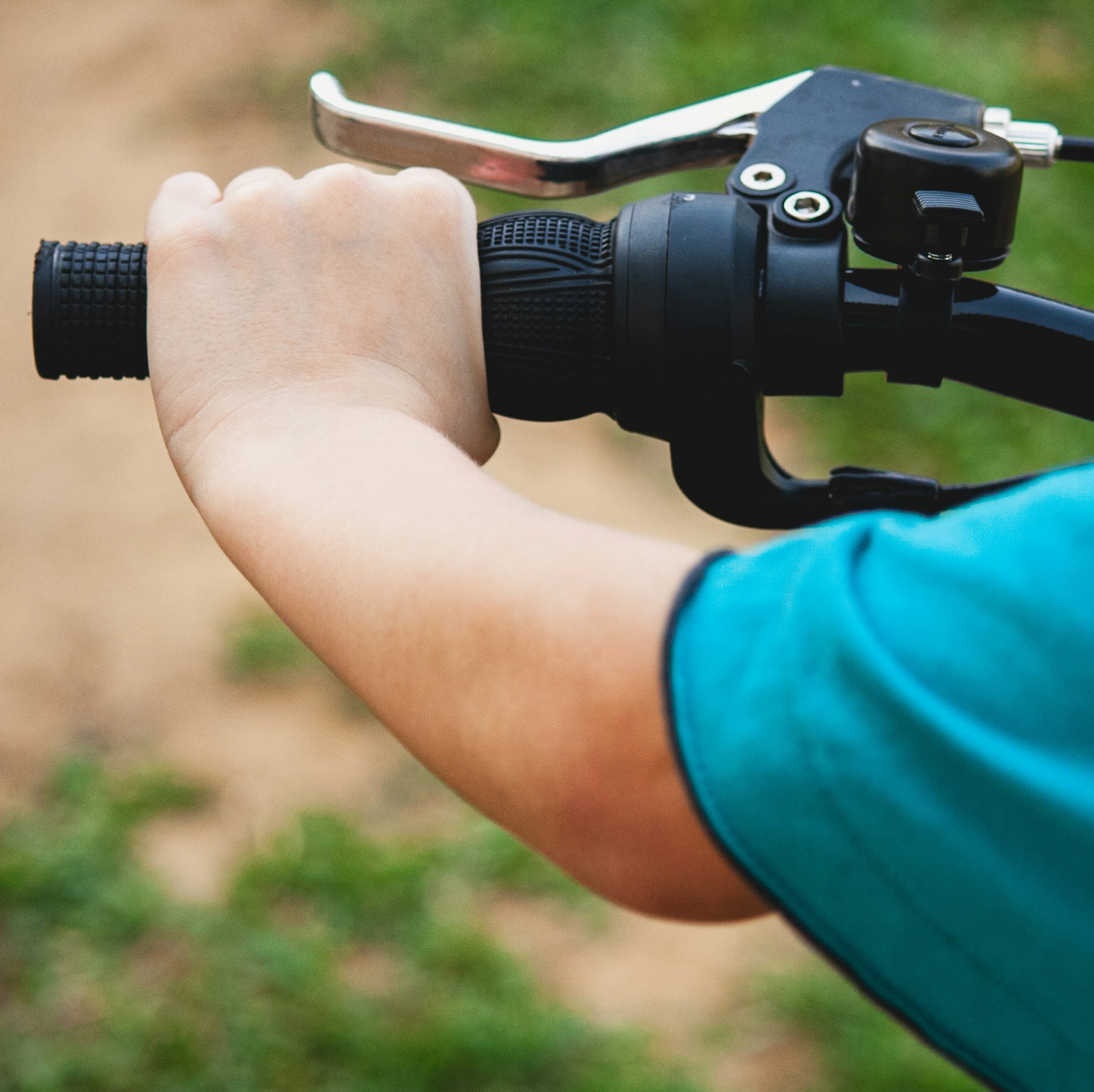 A hand on a bike's handlebar.