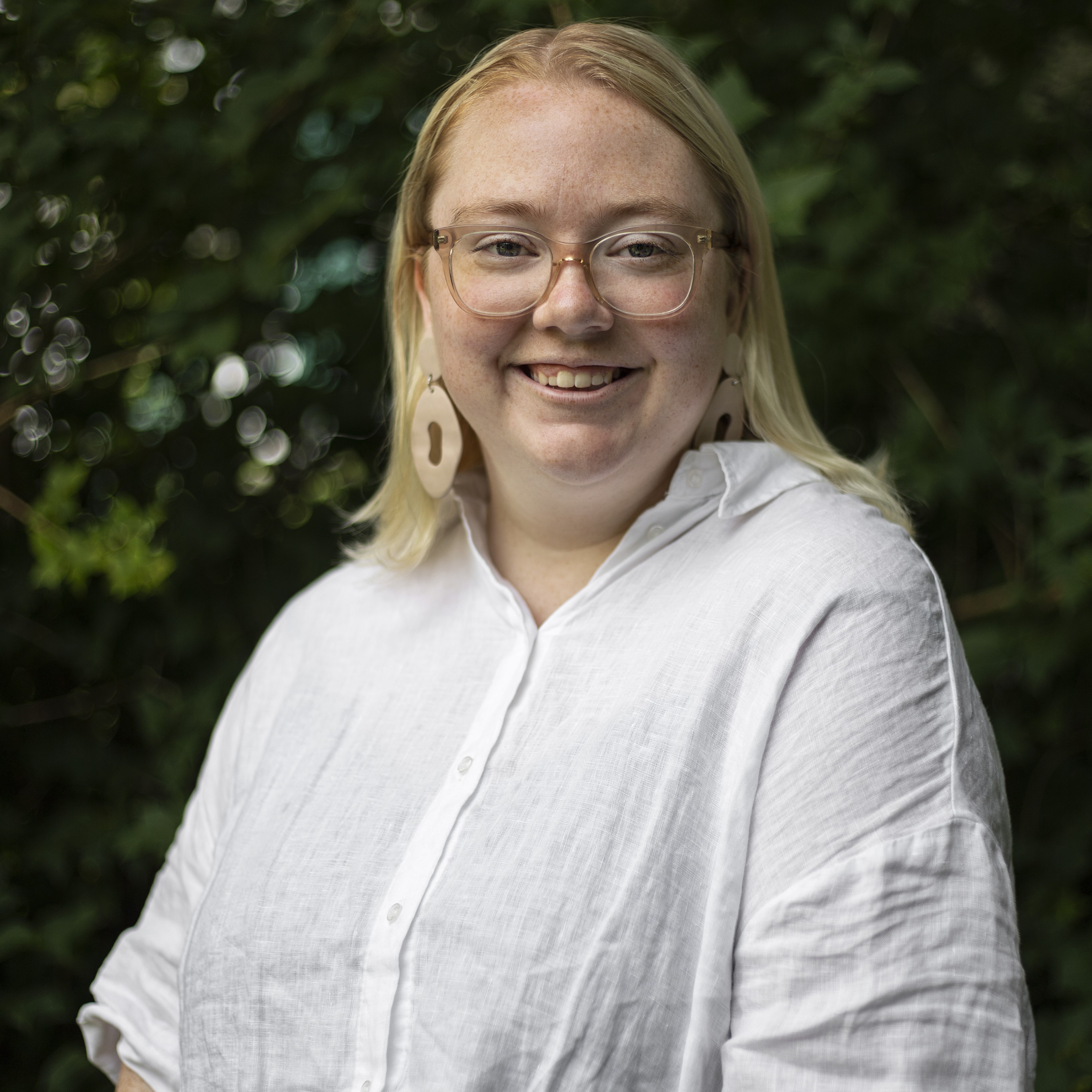 A photograph of Emily Clark, a woman in a white shirt smiling widely.