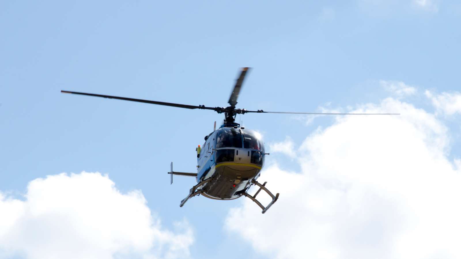 Helicopter flying over a cloudy blue sky. 