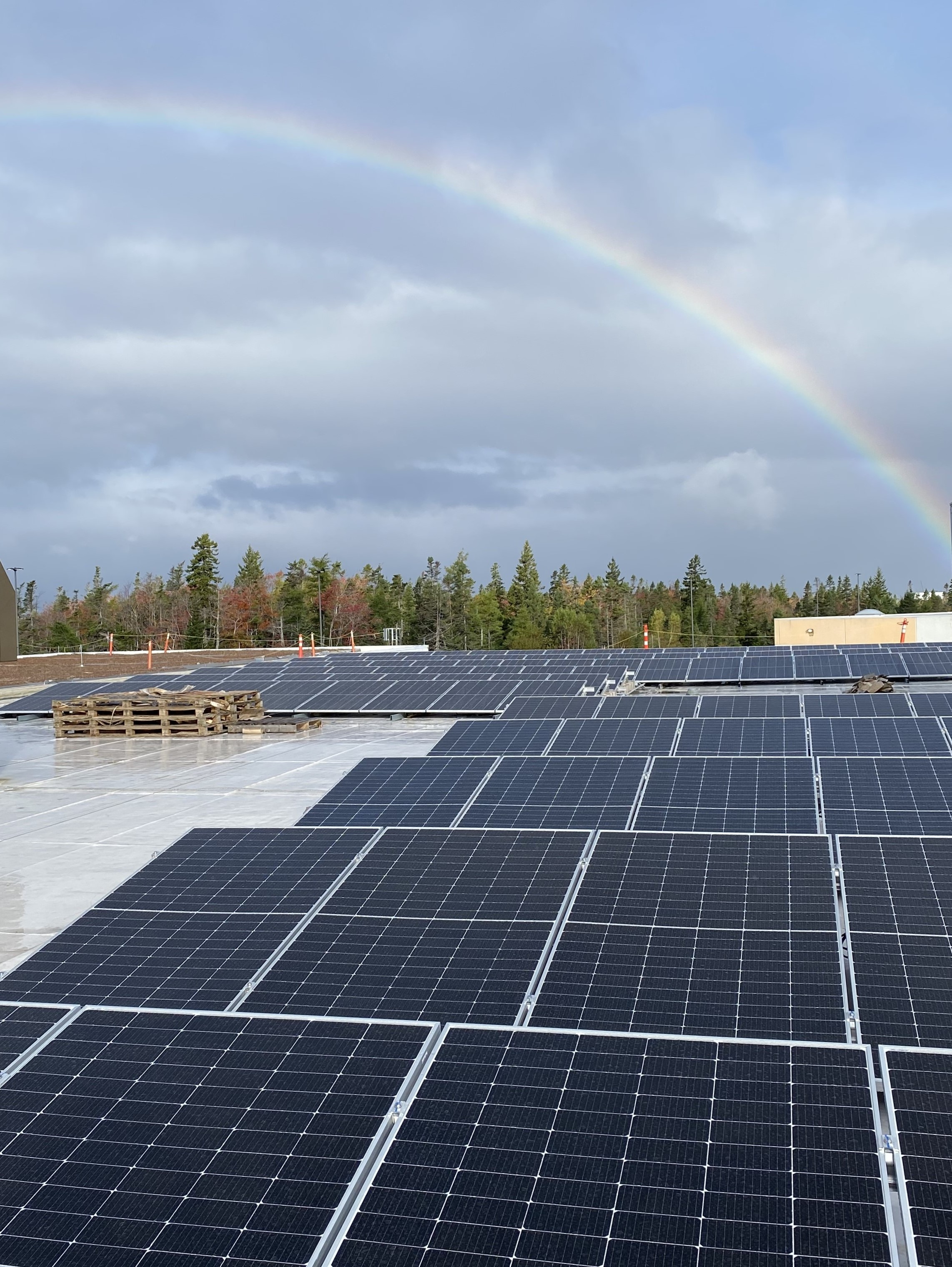 Solar panels on a rooftop with rainbox in background.