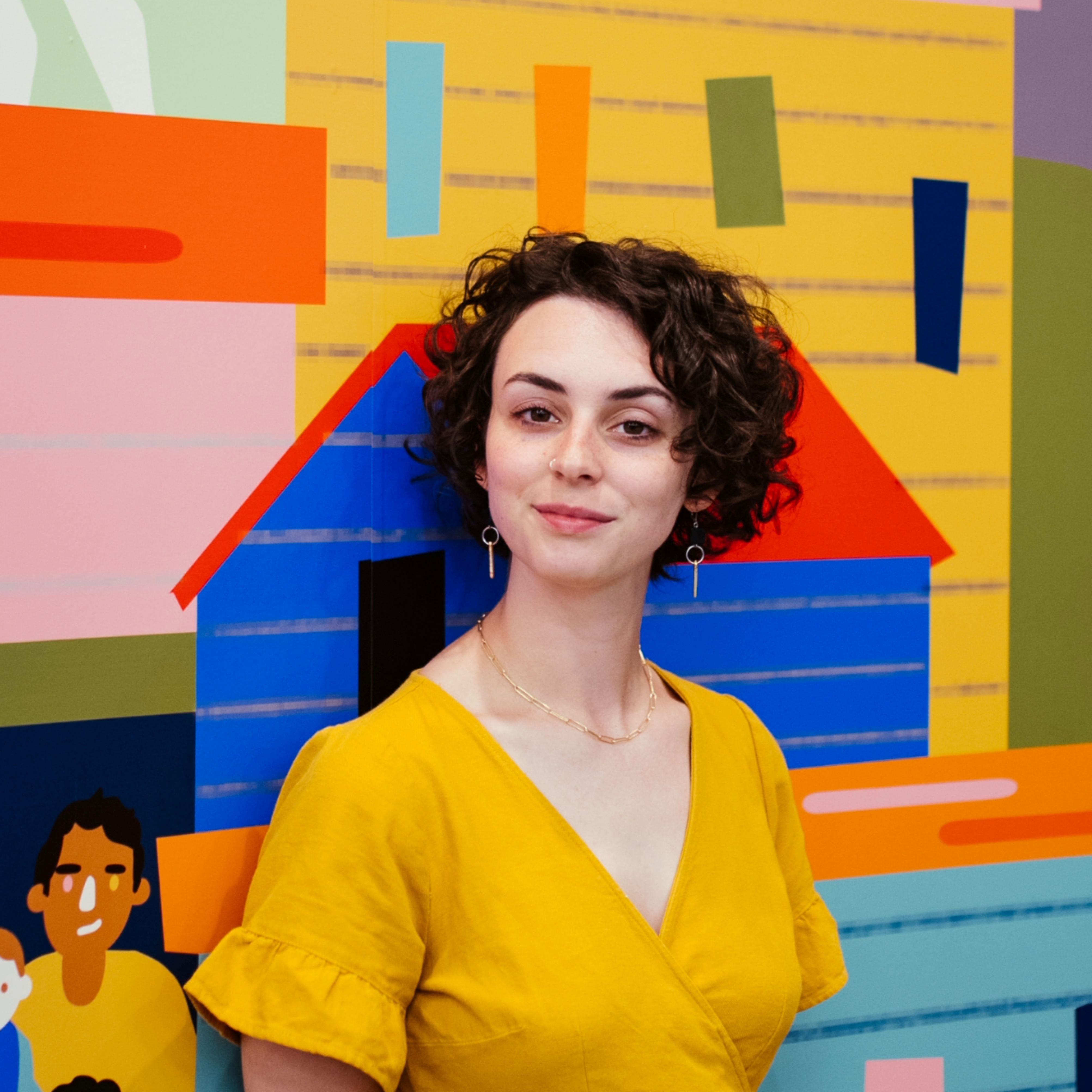 A photograph of Molly Margaret, a woman with brown hair wearing a yellow shirt.