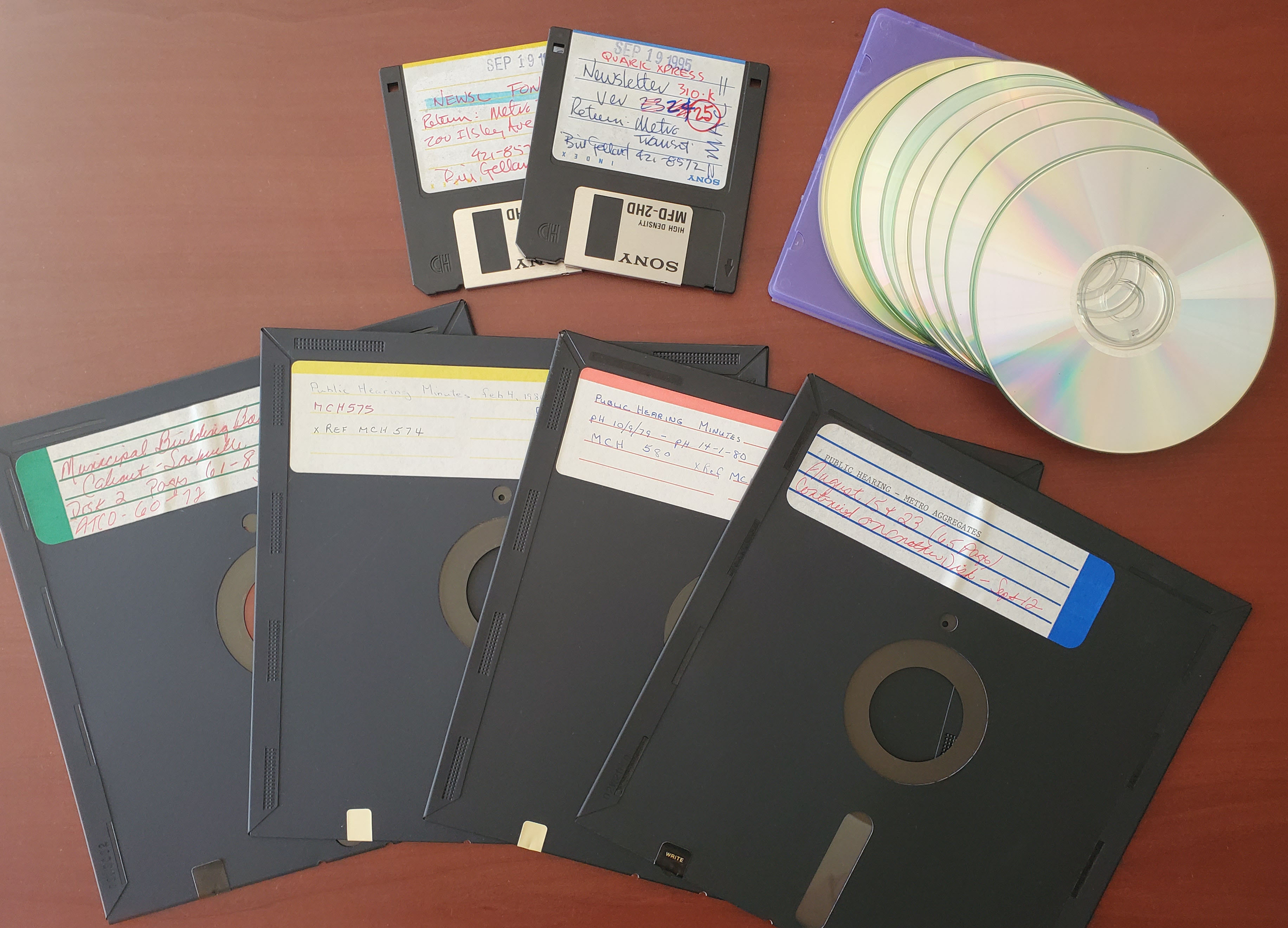 Overhead image of floppy disks, diskettes, and CDs on a table.