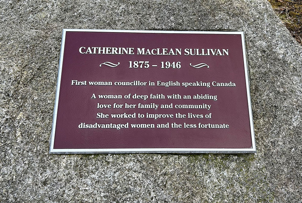 Colour photo of engraved plaque on stone: Catherine M. Sullivan 1874-1946 ~ First woman councillor in English speaking Canada ~ A woman of deep faith with an abiding love for her family and community.  She worked to improve the lives of disadvantaged women and the less fortunate