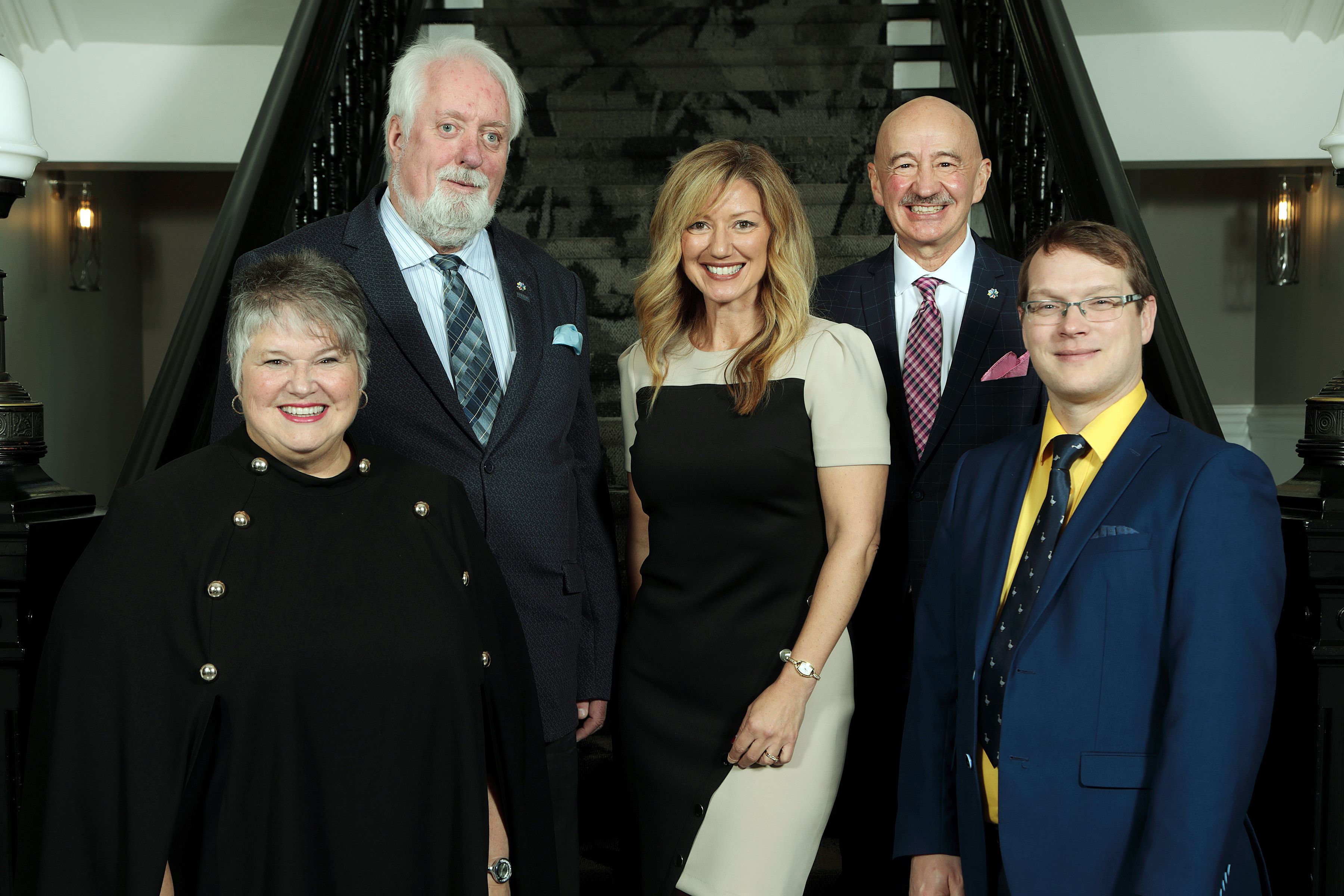 Members of Harbour East - Marine Drive Community Council stand together in front of the stairs inside City Hall