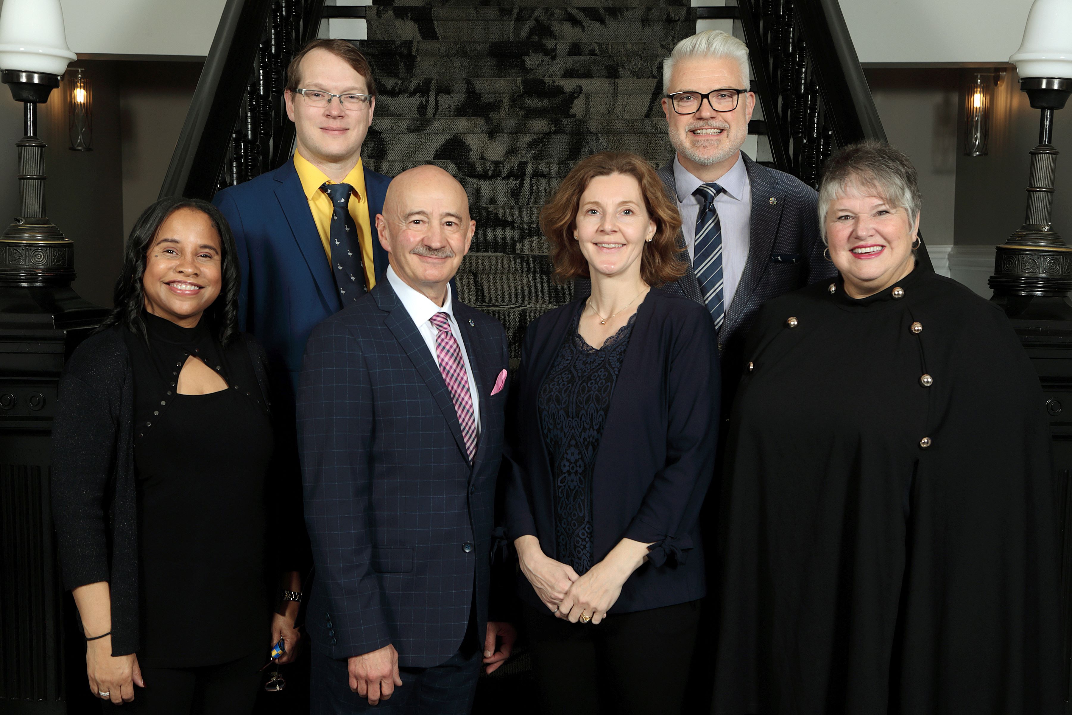 Members of Regional Centre Community Council stand together in front of the stairs inside City Hall