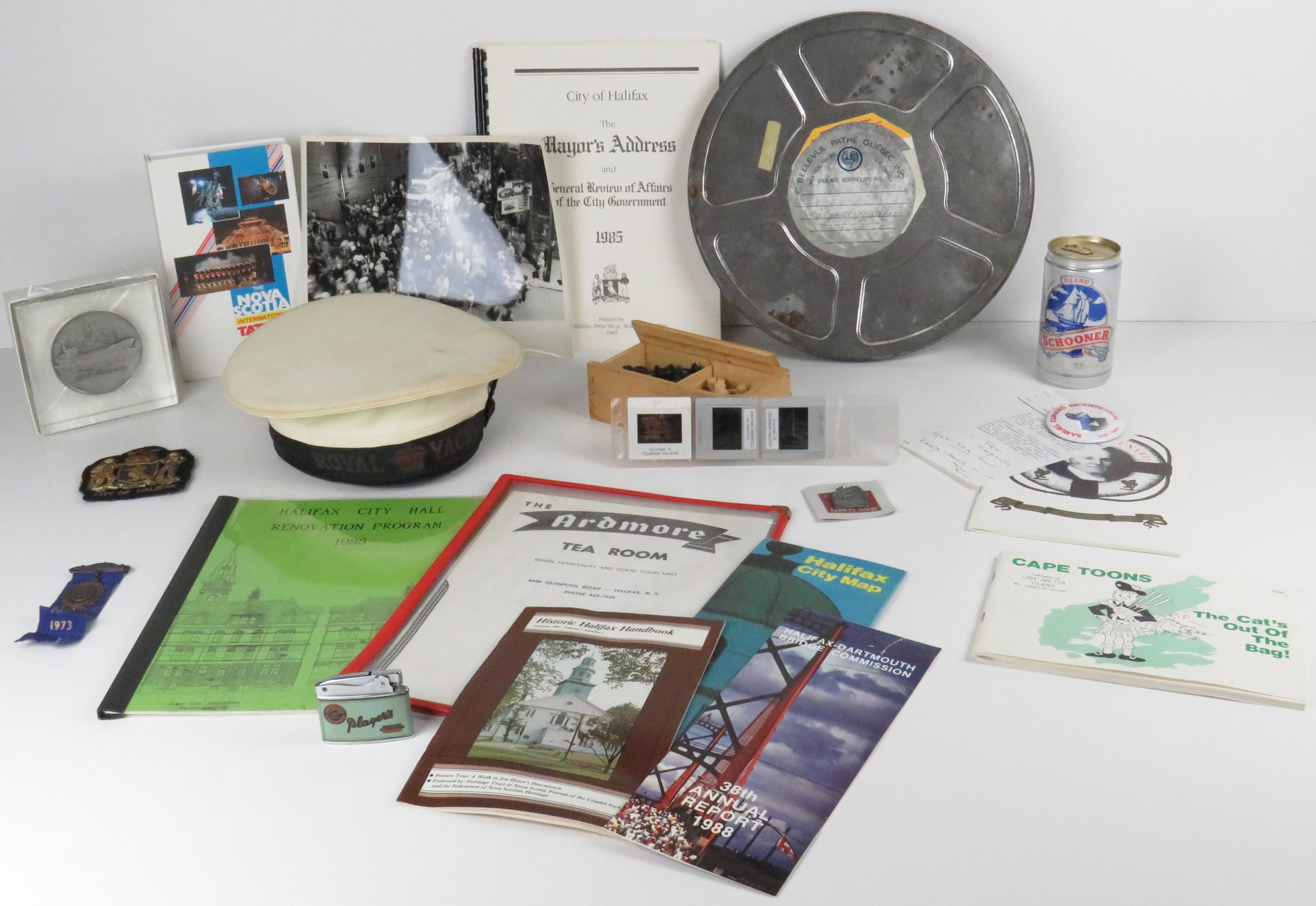 Collection of booklets, photos, a film canister, photos, sailor's hat, a beer can, a lighter, a medal, pins