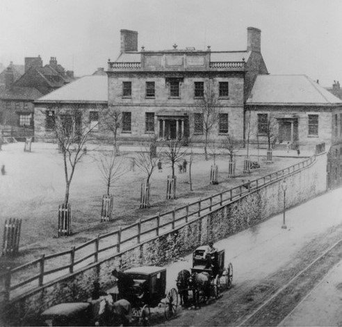 stone building fronted by small trees in parade with horse and wagons on Barrington Street