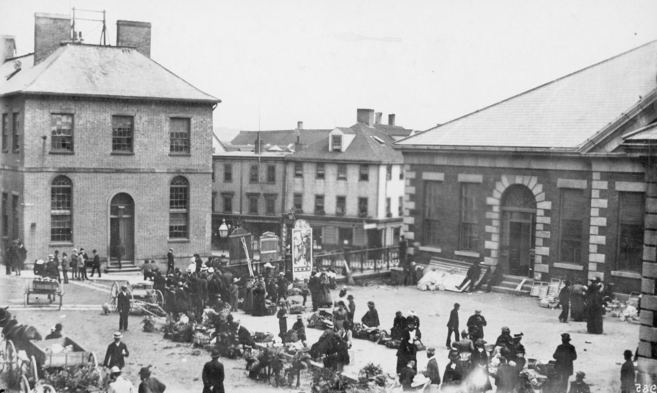 stone and brick buildings around a square with a market happening on the ground