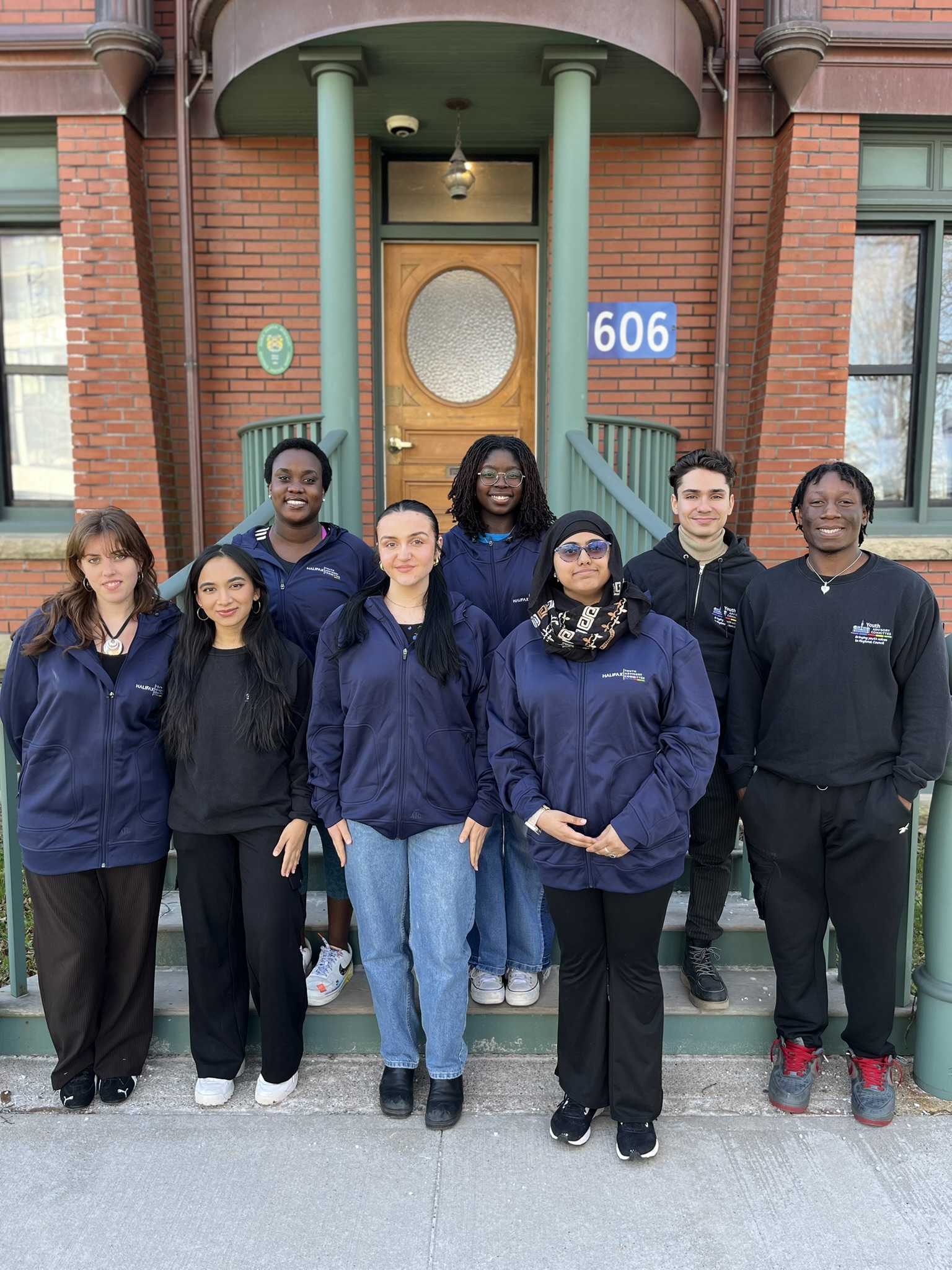 Members of the Youth Advisory Committee stand together on the front steps of the Power House Youth Centre.