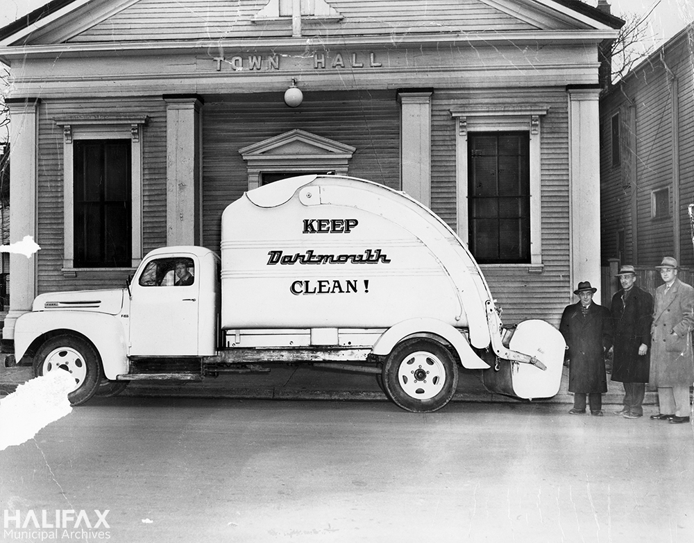 Three Dartmouth officials proudly displaying their new garbage truck outside the Town Hall on Ochterloney St.