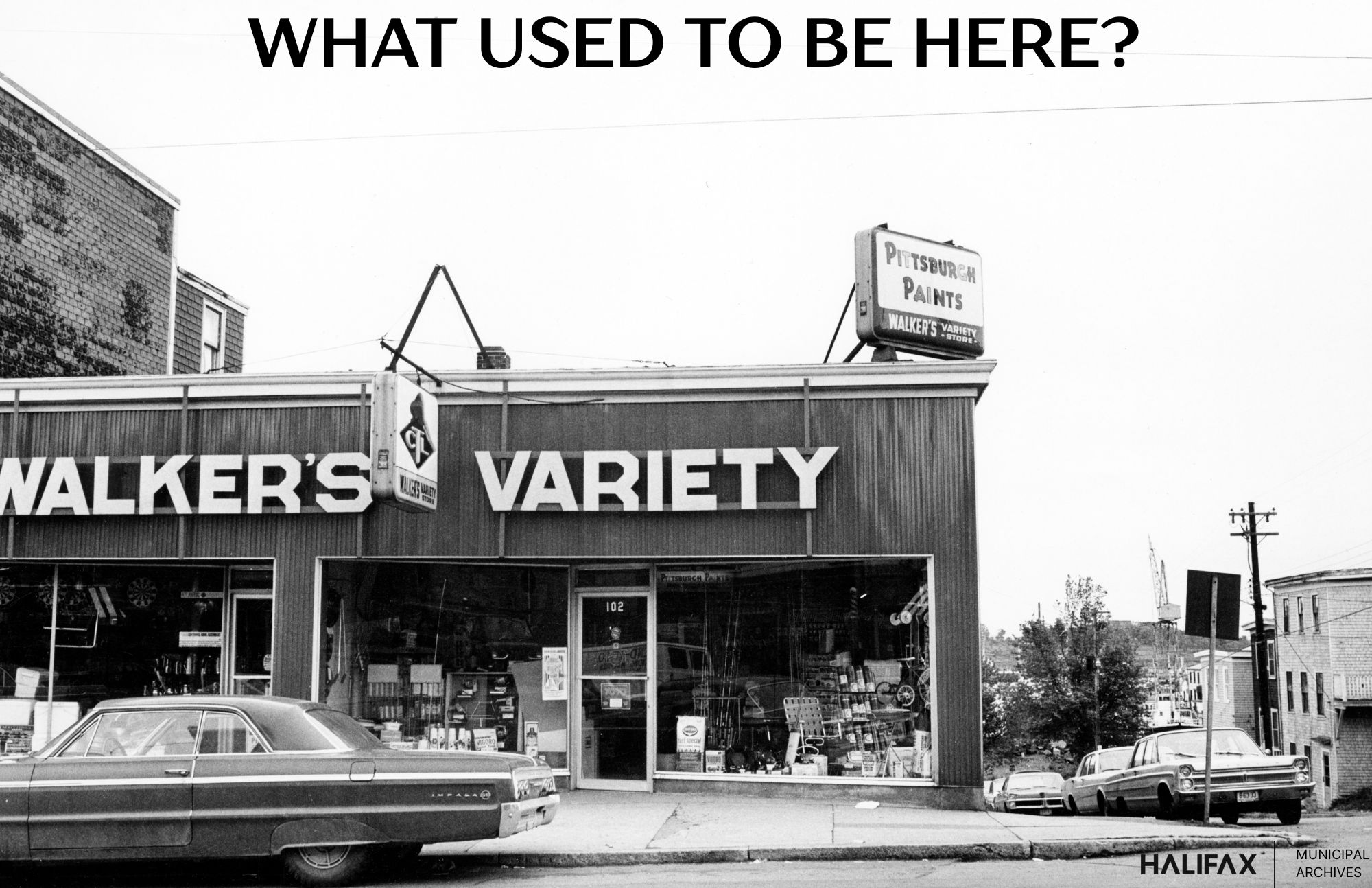 Black and white photograph of a variety store with cars parked in front.